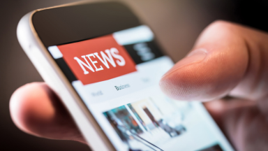 A phone displays a news website.